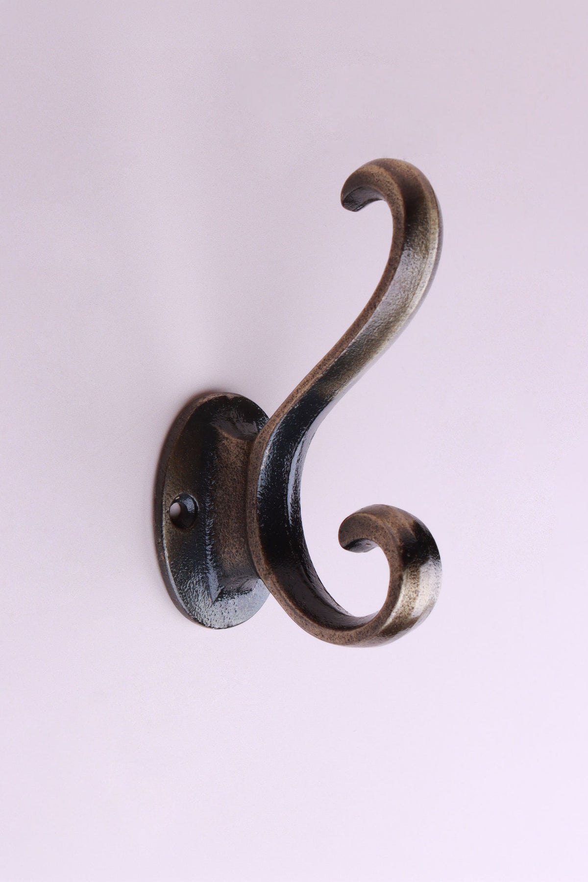 Curl Tip Hook: cast iron double hook with curled scroll ends, on an oval back plate, antique brass finish