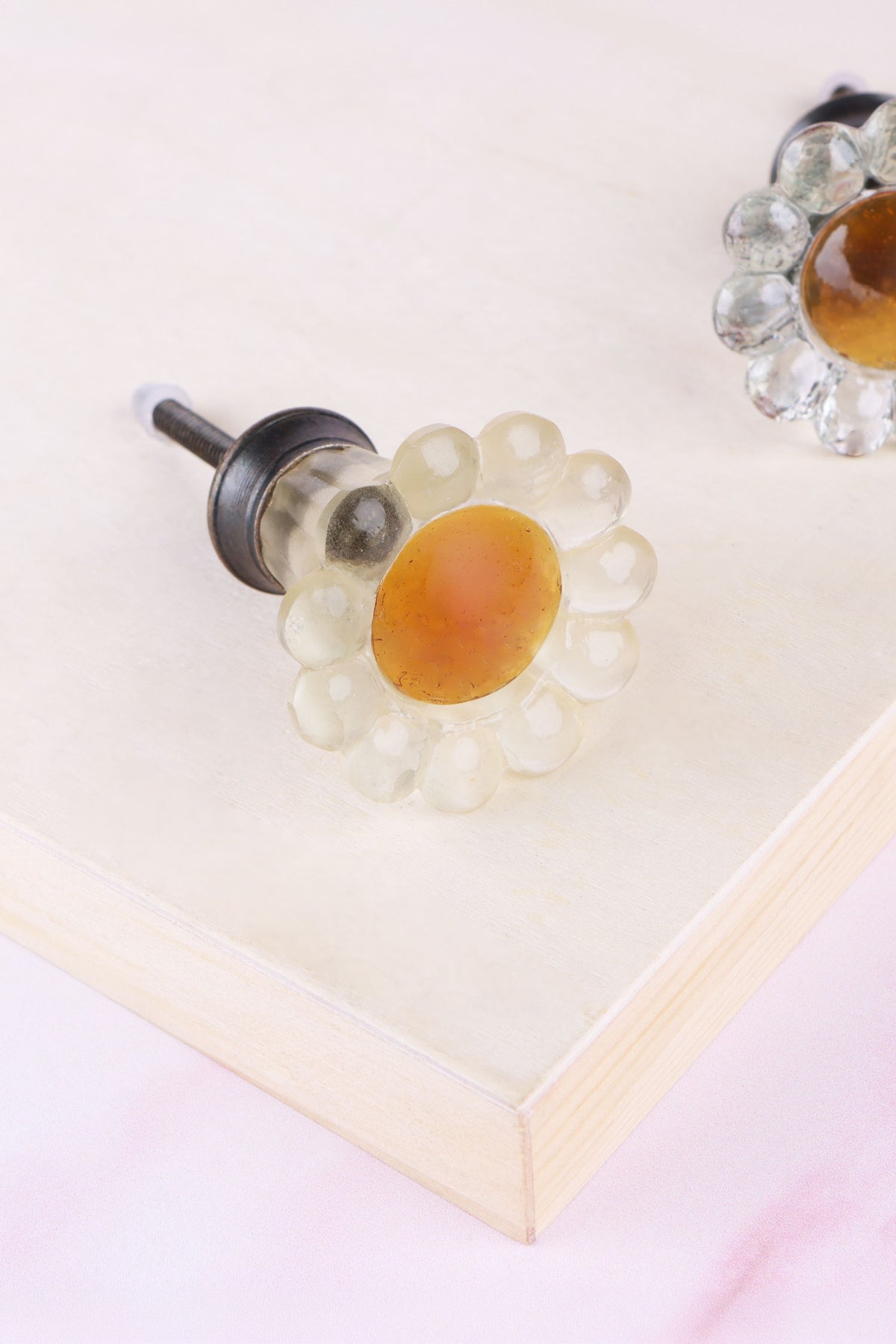 Ivory daisy glass cabinet knob: soft cream petals around an amber glass centre, on a ribbed glass stem and antique brass finish base