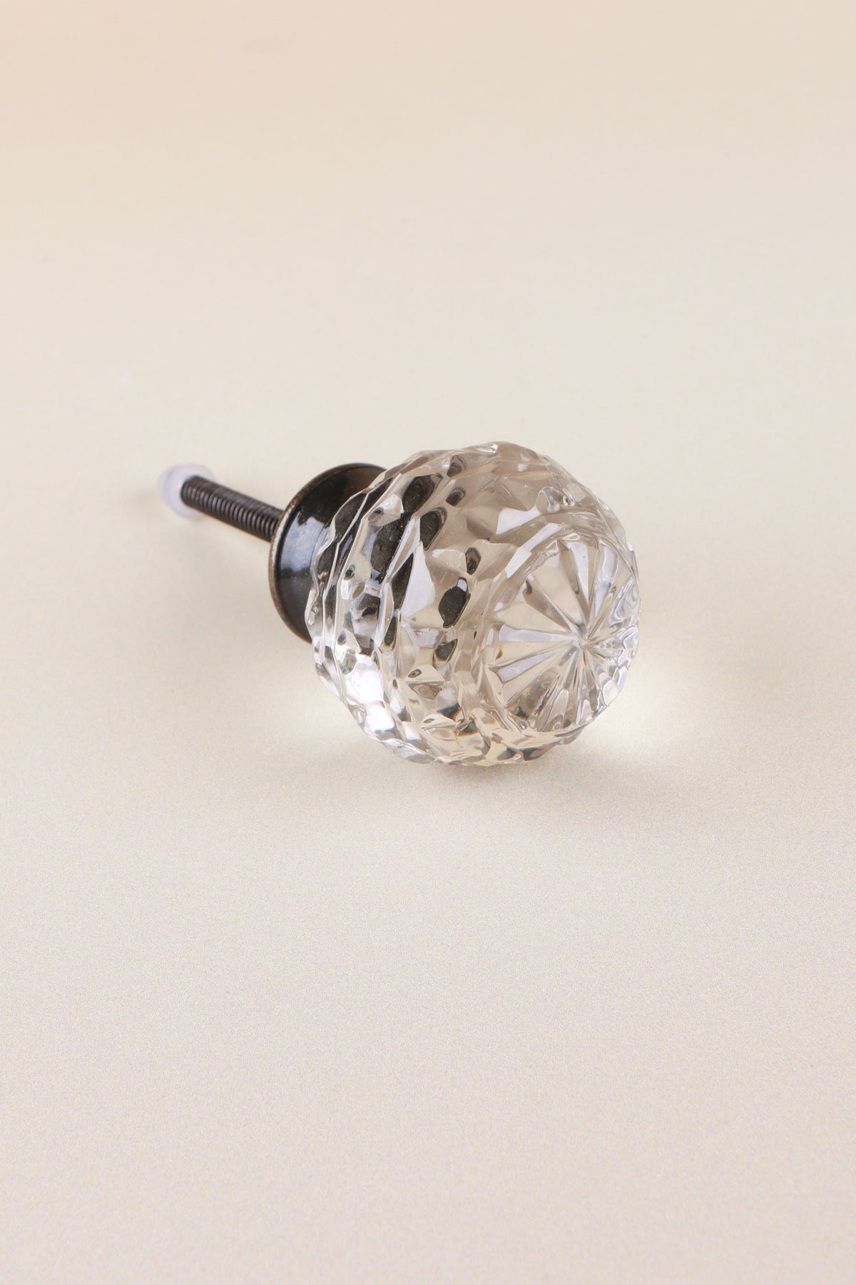Clear faceted glass ball cabinet knob with a star cut on the front, on an antique brass finish base with its fixing bolt