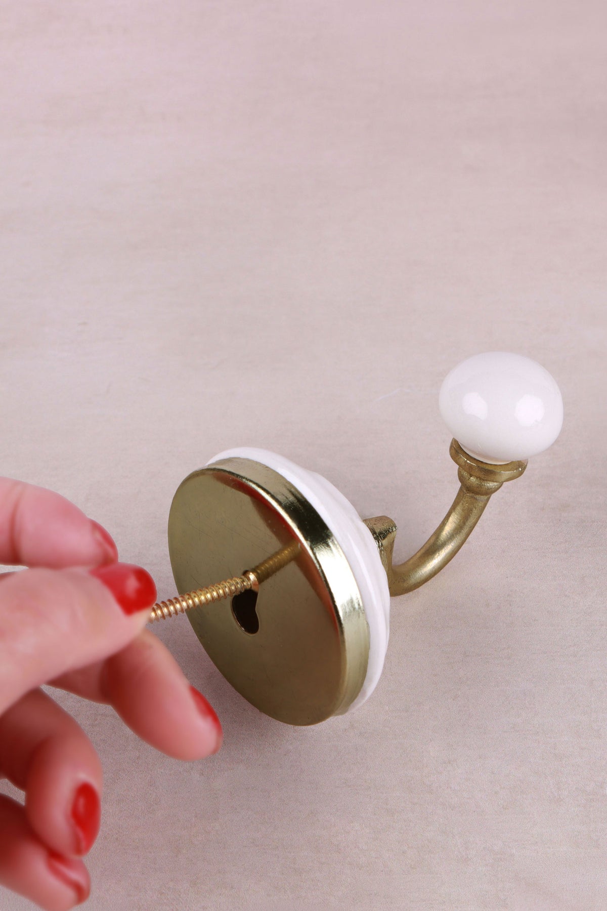 Fixing a floral ceramic wall hook — the screw goes through the centre of the plate