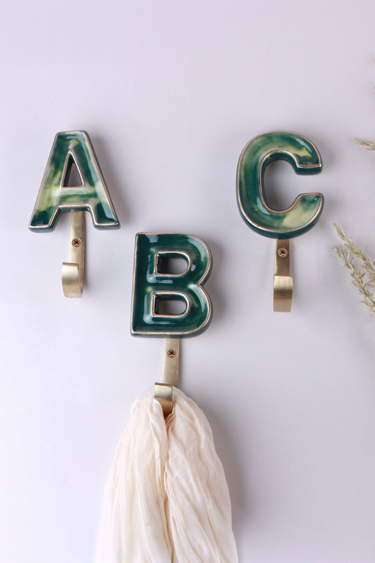 Green ceramic letter hooks on the wall, second view