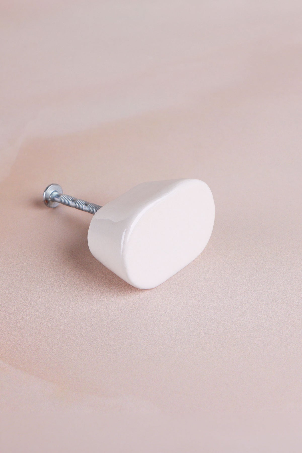 Cream oval ceramic cabinet knob with its fixing bolt