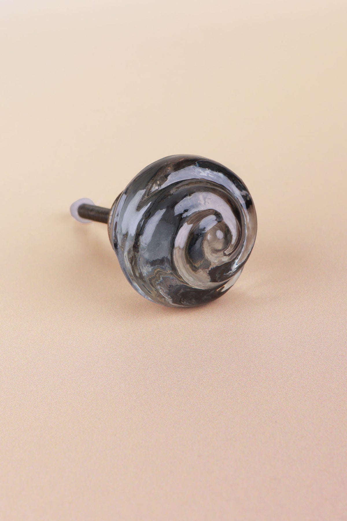 Smokey Grey small rose glass cabinet knob with a swirl curling into the centre, on an antique brass finish base