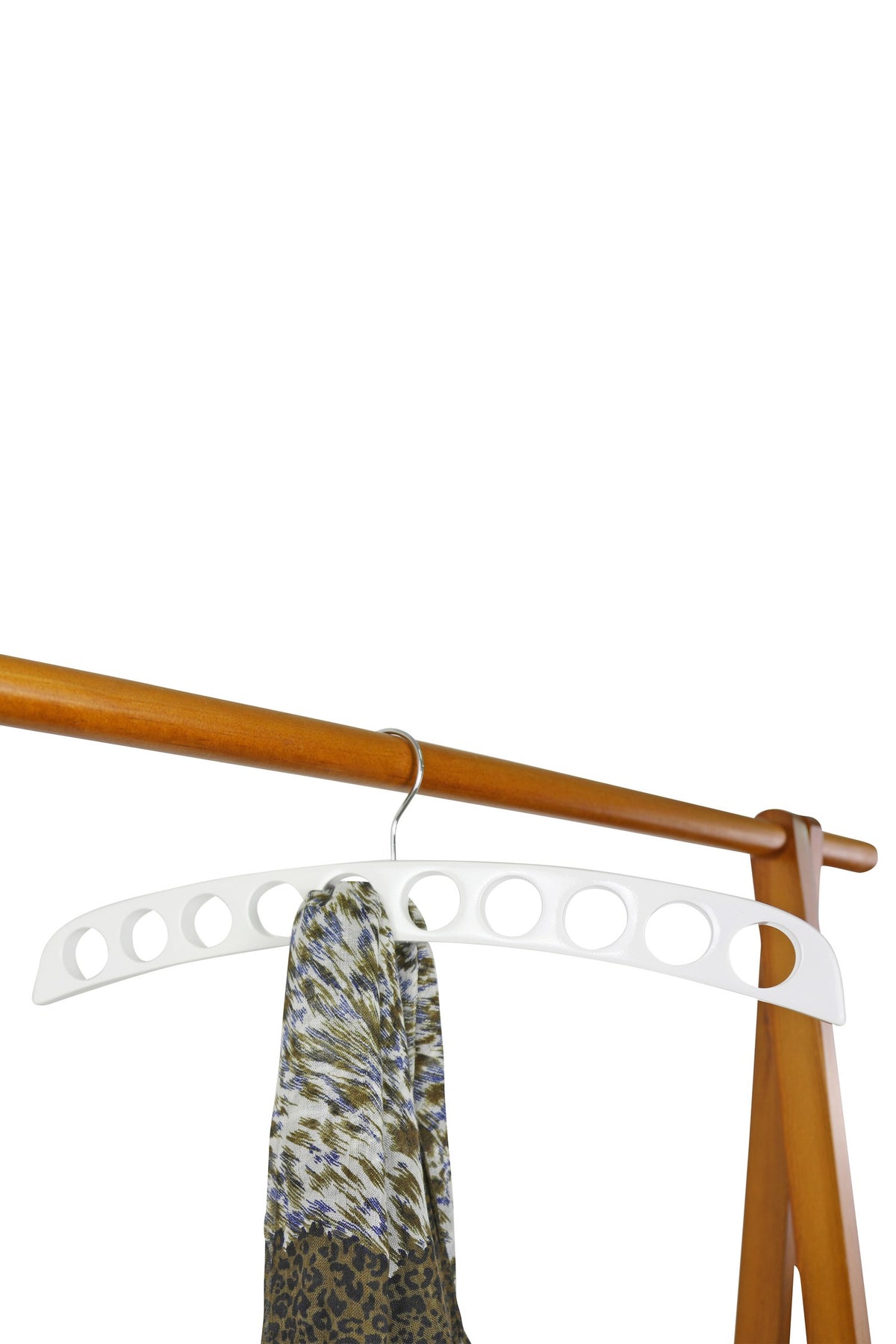 White wooden scarf hanger on a wooden rail with a printed scarf pulled through one of the holes