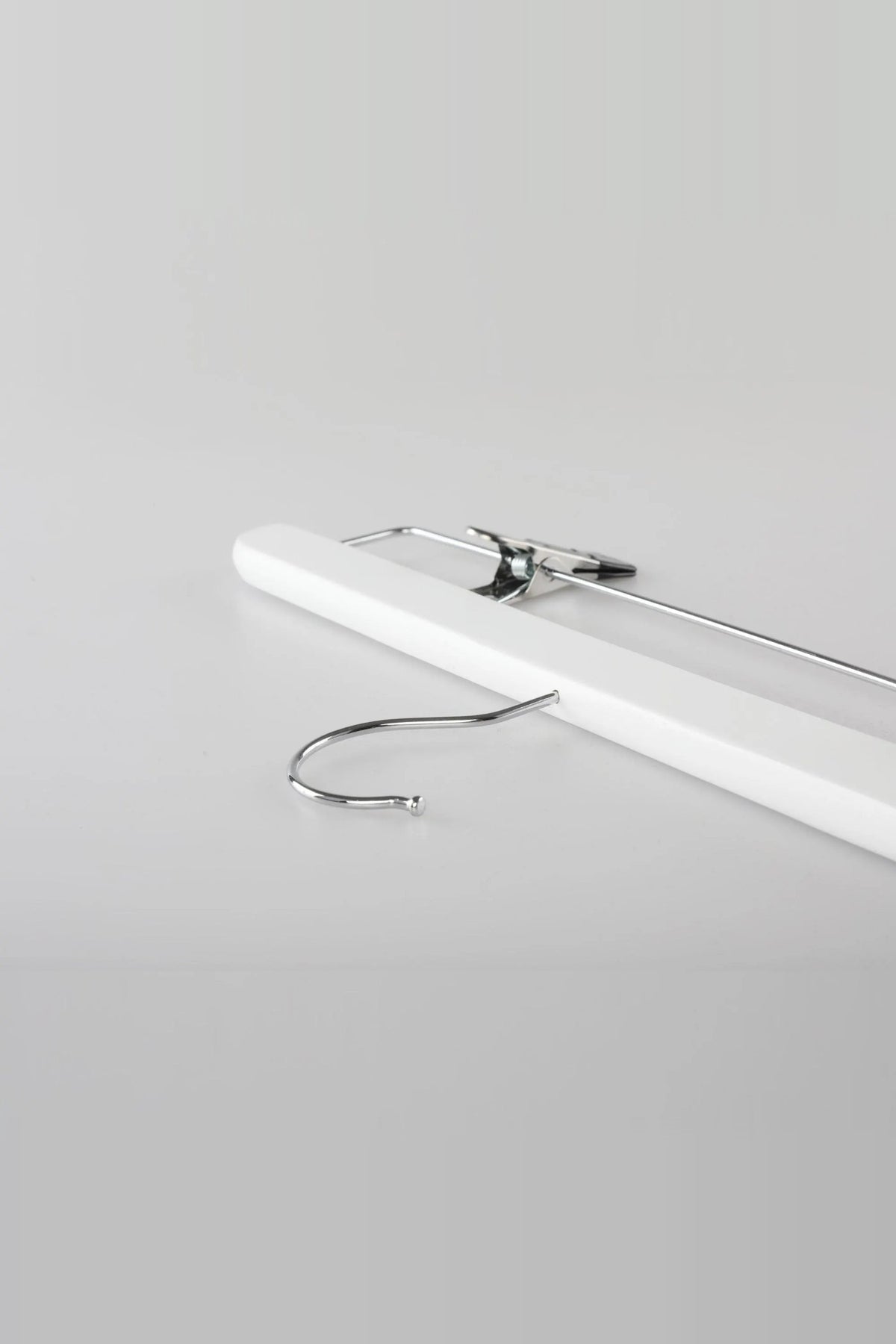 White wooden clip hanger lying flat, showing the metal hook and a clip