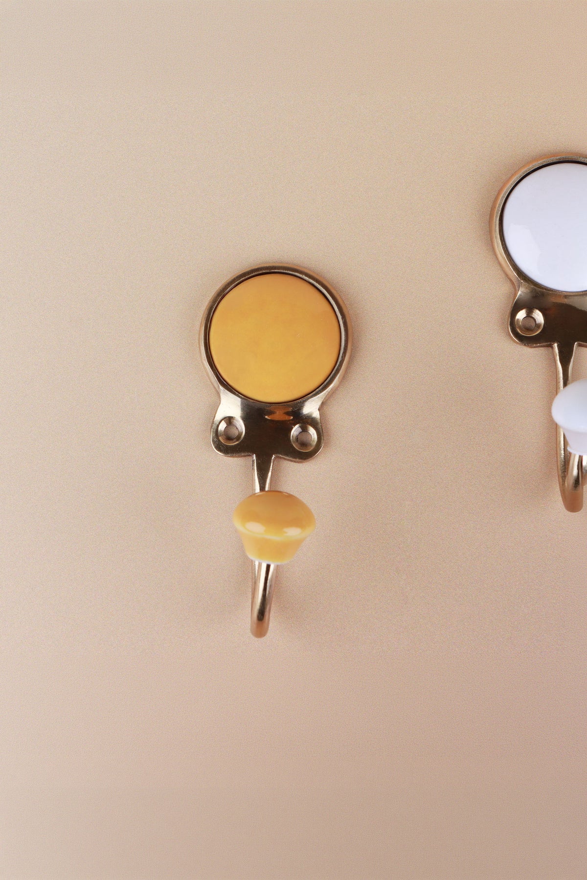 Yellow ceramic coat hook: warm mustard yellow disc in a gold-tone frame with a matching yellow ceramic knob