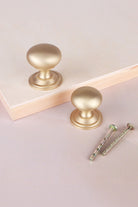 Bun cabinet knob in satin brass, shown in 32mm and 38mm