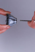 Black ceramic knob held between the fingers with its M4 bolt, to show the size