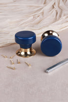 Pair of navy blue ceramic mortice door knobs with flat faces on polished brass roses, with the 8 mm spindle and fixing screws