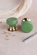 Pair of sage green ceramic mortice door knobs with flat faces on polished brass roses, with the 8 mm spindle and fixing screws