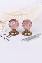 Pair of blush pink faceted glass mortice door knobs on antique brass roses, with the square spindles and fixing screws