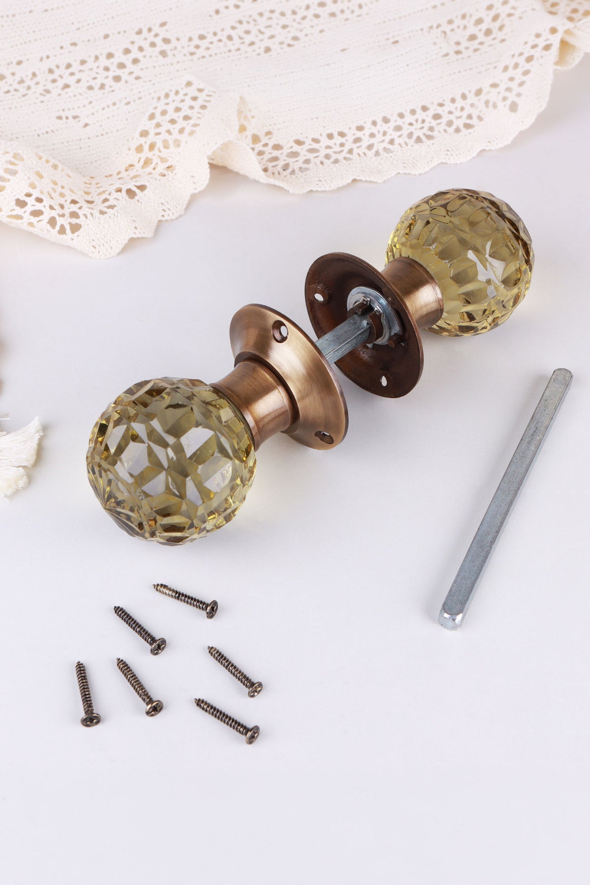 Ivory glass mortice door knobs joined by the spindle through their antique brass roses, as they sit on a door