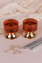 Two amber glass cylinder door knobs standing on their polished brass roses, with the square spindles and fixing screws