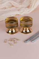 Two ivory glass cylinder door knobs standing on their polished brass roses, with the square spindles and fixing screws