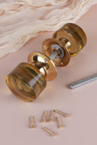 Ivory glass cylinder mortice door knobs joined by the spindle through their polished brass roses, as they sit on a door