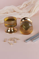 Pair of ivory glass cylinder mortice door knobs on polished brass roses, one standing and one on its side, with the square spindles and fixing screws