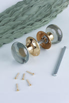 Clear glass dome mortice door knobs joined by the spindle through their polished brass roses, as they sit on a door