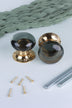 Pair of smokey grey glass dome mortice door knobs on polished brass roses, one standing and one on its side, with the square spindles and fixing screws