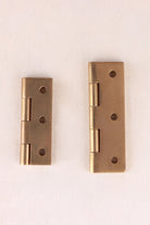 Aged brass butt hinge open, showing the knuckle and solid brass screws