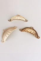 Scalloped cup pulls on a drawer front, ribs catching the light
