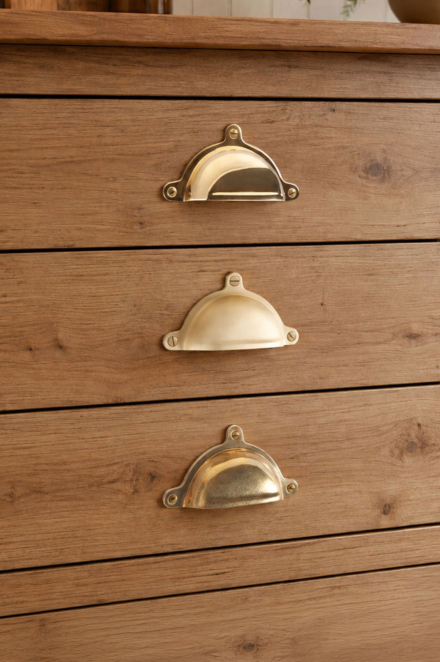 Three finishes of the Classic cup pull side by side on a kitchen drawer