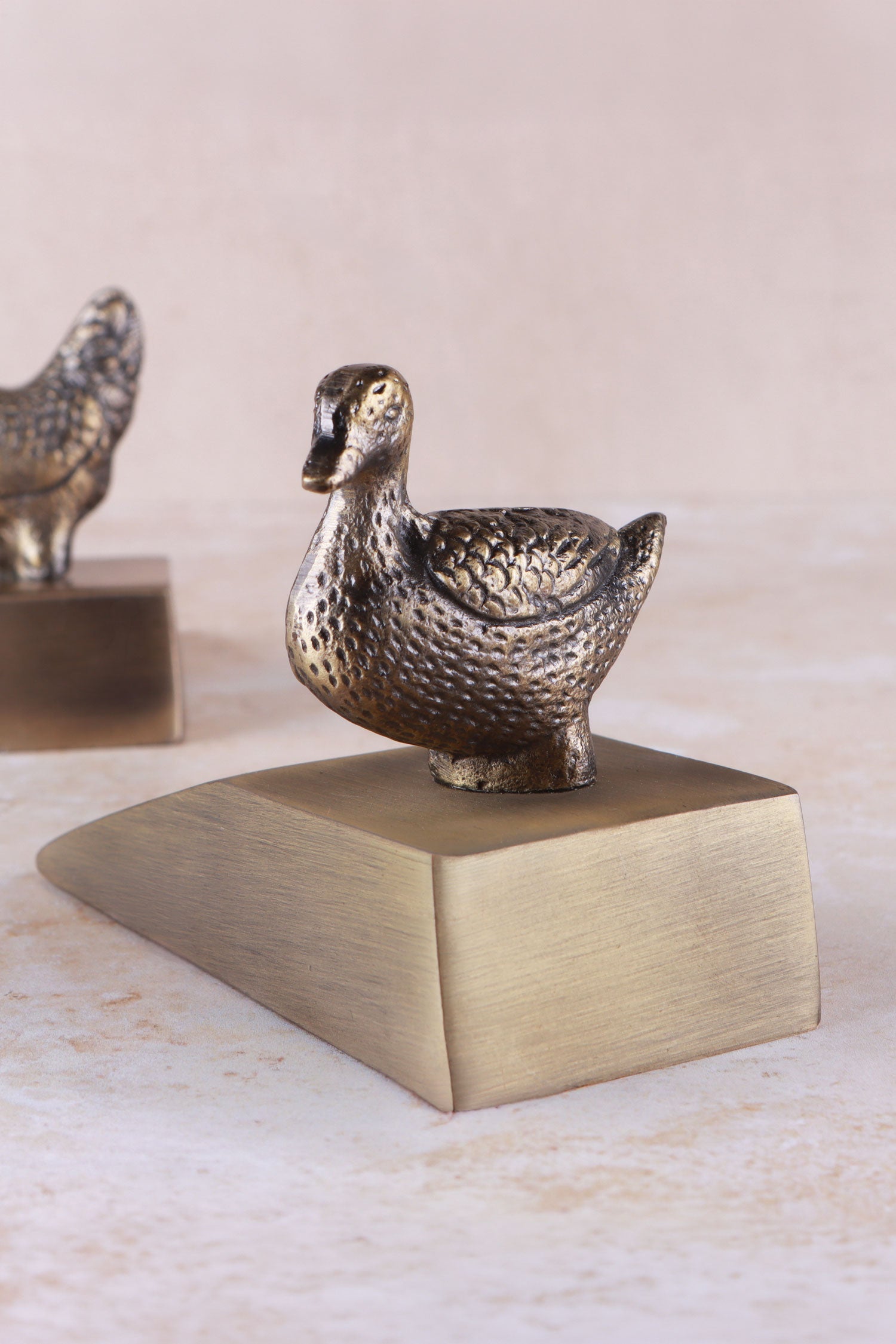 Duck door stopper in antique brass, side view