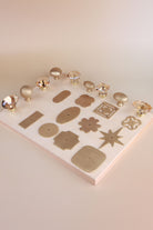 Eleven satin brass backplate shapes laid out on a board with champagne crystal and satin brass knobs