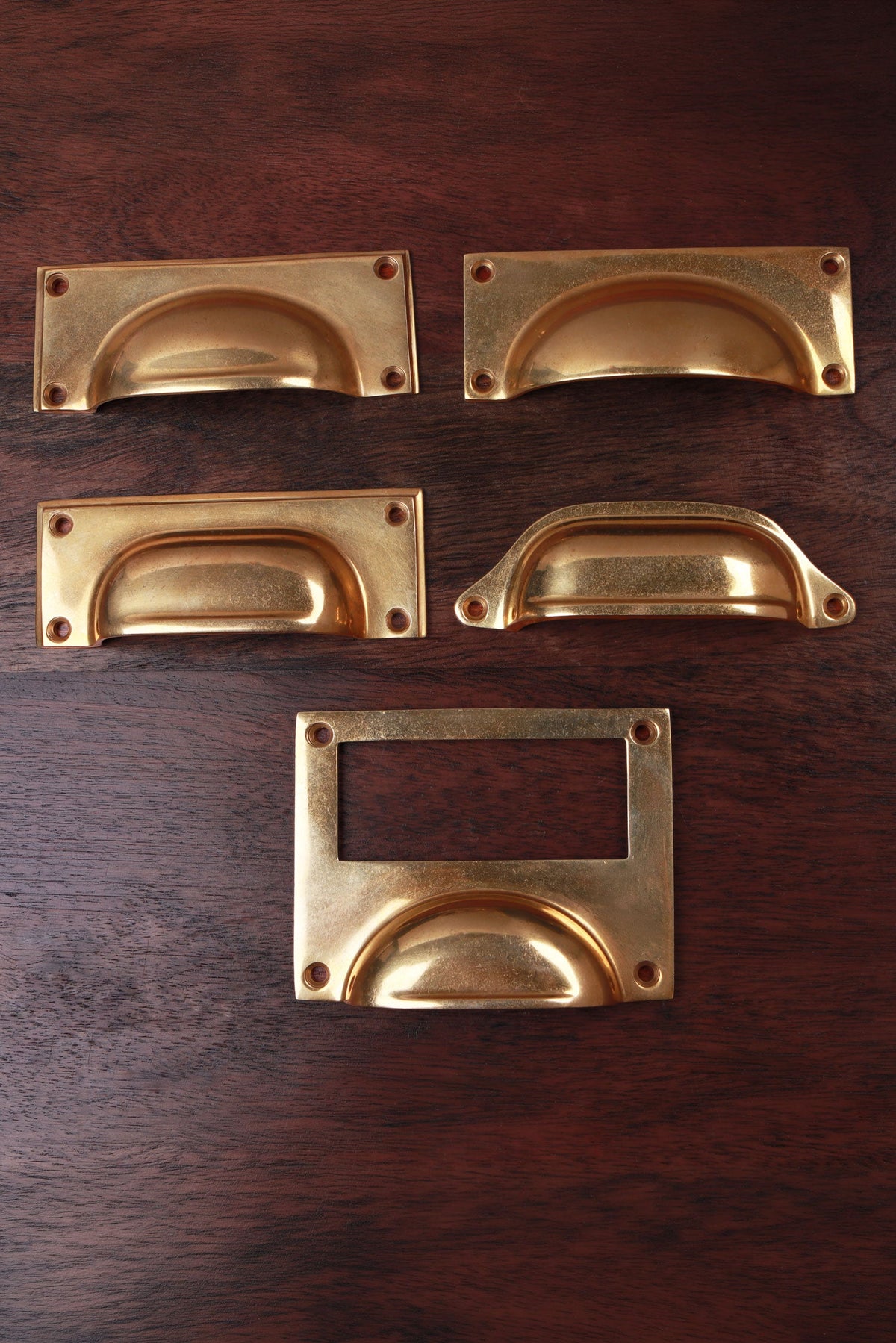Five aged brass cup pull shapes — bevelled plate, square plate, rounded plate, classic and card frame