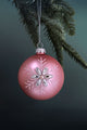 Pink Christmas bauble with jeweled snowflake design hanging from pine branch, G Decor