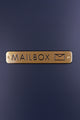 Gold mailbox sign with engraved lettering on a matte dark surface, luxury home hardware by G Decor