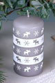 Grey decorative candle with white moose and snowflake patterns from G Decor, on a festive table