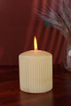 Textured cream pillar candle burning on wooden surface, luxury G Decor home accessory