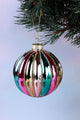 Colorful glass Christmas bauble with gold glitter stripes hanging on pine tree branch, G Decor