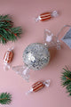 Sparkling candy-shaped glass ornament with sequins, striped sweets, and pine branches.