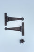 Black metal T-hinges with screws on a light blue background, G Decor luxury hardware