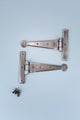 Pair of silver metal T hinges with screws on light blue background, G Decor hardware