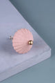 Pink scalloped ceramic drawer knob with brass center on light blue background, G Decor hardware