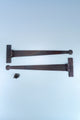 Pair of black decorative T-hinges with screws on a light blue background, G Decor hardware