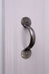 Silver metal cabinet pull handle on a white paneled door, G Decor luxury hardware