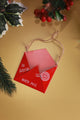 Red metal Christmas ornament shaped like an envelope to Santa, North Pole, on gold background