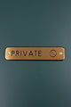 Luxury brass PRIVATE door sign with black engraved letters on a dark green wall from G Decor