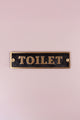 Luxury brass toilet door sign with black background on light pink wall, G Decor hardware