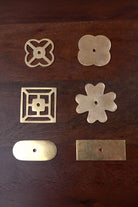 Six aged brass backplates — pierced and solid quatrefoil, square fretwork, flower, oblong and rectangle