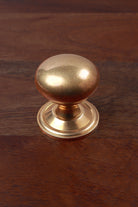 Aged brass bun cabinet knob on a stepped rose