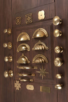 Angled view of the aged brass knobs, cup pulls, D handles and backplates on a panelled door