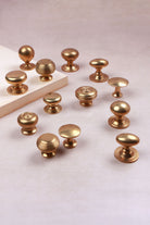 Thirteen aged brass cabinet knob styles grouped together