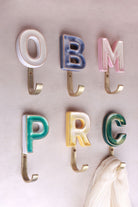 Ceramic letter hooks in blue, yellow, green and pink, mixed on one wall