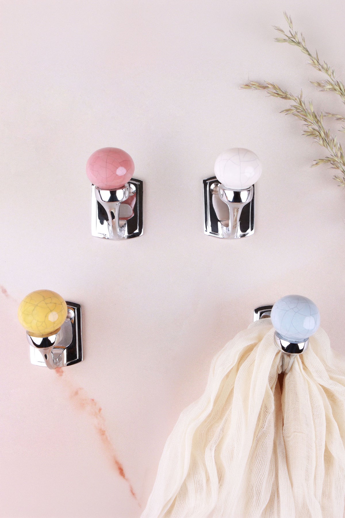 Crackle glaze ceramic ball hooks in terracotta, antique ivory, mustard ochre and smoke grey on pink marble, a cream scarf on the smoke grey hook