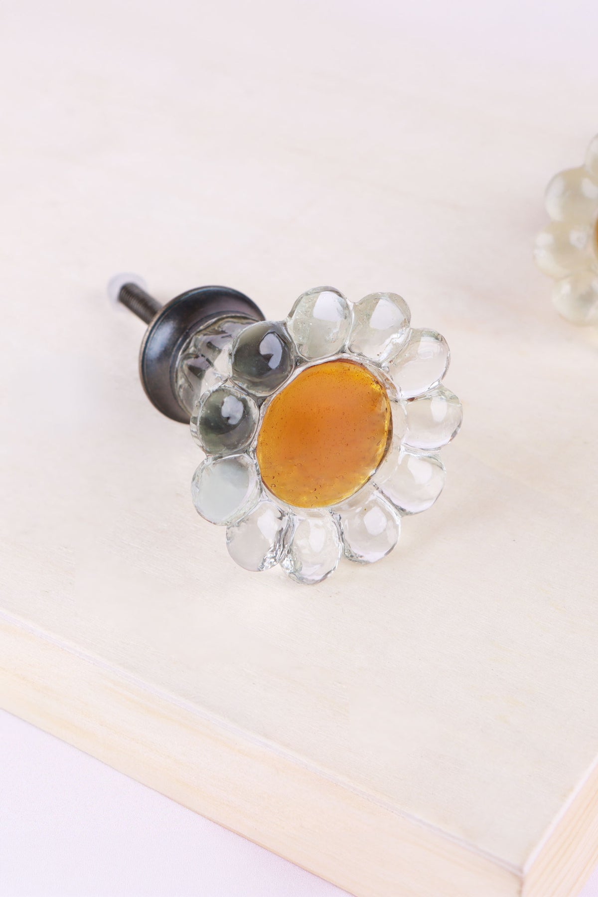 Clear daisy glass cabinet knob: glossy clear petals around an amber glass centre, on an antique brass finish base