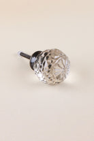 Clear faceted glass ball cabinet knob with a star cut on the front, on an antique brass finish base with its fixing bolt